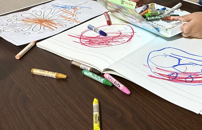 子どもが描いたクレヨンの絵とノート